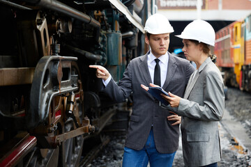 businesspeople checking and pointing to the train on construction site