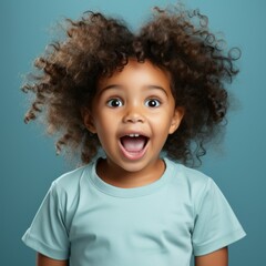 Portrait of a surprised little African girl with big eyes and an open mouth. Closeup face of a shocked African-American child on a blue background. Amazed kid in a blue shirt looking at the camera - 733021124