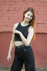 Portrait of a young beautiful long-haired girl in dark clothes on a summer street.