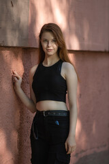 Portrait of a young beautiful long-haired girl in dark clothes on a summer street.