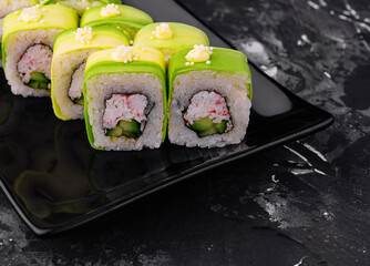Avocado Sushi roll with crab on black plate