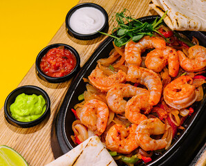 Fried large shrimp with onions and peppers in a frying pan