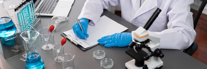 Closeup hand recording clinical data result after conducting chemical experiment in medical...