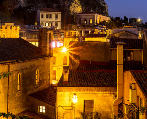 evening landscape of antique night european town with flashlights, buildings and mountains, Italian...