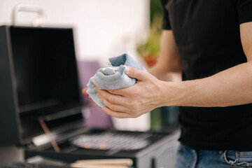 Close-up of male using towel to wipe dirt from hands while the fire is burning in the grill
