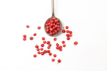 Red peppercorns in iron spoon on white background. Organic spice. Dry red pepper grain.