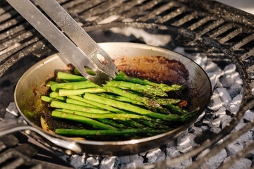 Close-up of healthy frying green asparagus with butter and garlic on carbon steel frying pan....