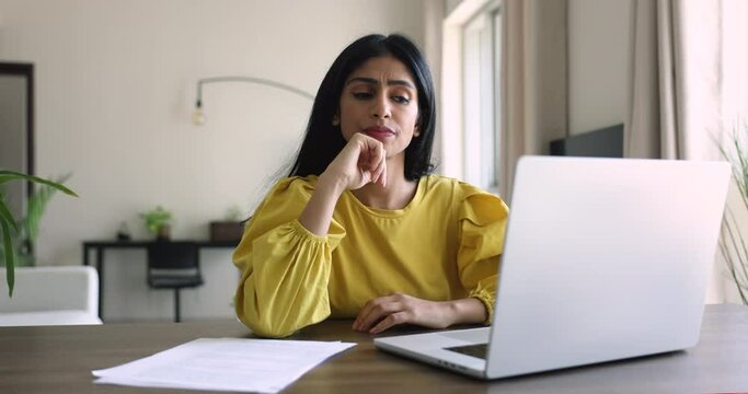 Indian woman staring at laptop, feels frustrated, got bad news, looks disappointed lost document, unsaved data, problems with device, unpleasant e-mail about dismissal, mistake, having business issues