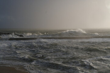 A view of the jetty of a small French harbor on a stormy day. Batz-sur-Mer, France - February 10, 2024.