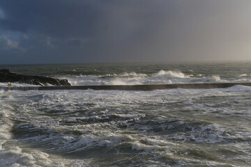 A view of the jetty of a small French harbor on a stormy day. Batz-sur-Mer, France - February 10, 2024.