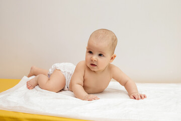 A baby in a diaper crawling on a couch in a hospital.
