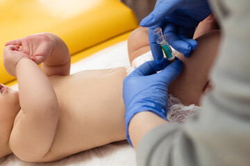 Pediatrician administring vaccination to little baby.  Pediatrician is giving injection in leg to small baby. Close up. Children health care and disease prevention.
