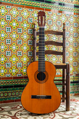 GUITAR AND A TYPICAL CHAIR ON ANDALUSIAN TILES BACKGROUND IN SEVILLE FAIR. SPANISH FLAMENCO.