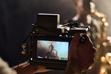 Closeup of videographer holding professional camera equipment while filming music video for Black...