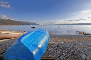 Vernacular rowboats aground on the shore, pebble Saraiste beach on the lakeside along Kosta Abrash...