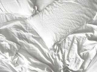 Top view of cozy bedding sheets and pillow. White striped satin bed linen. Mess on bed.