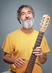 Aged man with a guitar on grey background