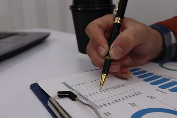 Close up of male hand working with business and forex chart of downward trend and financial downfall concept.