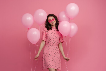 pretty young woman posing isolated on pink studio background with pink air balloons