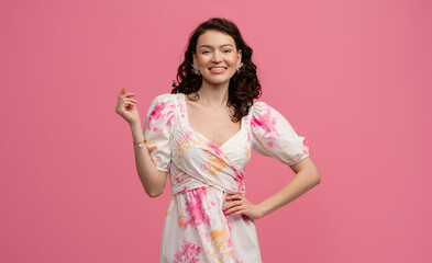 pretty young woman posing isolated on pink studio background in dress