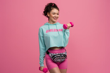 smiling happy beautiful woman in stylish sports outfit doing workout on pink background isolated in...