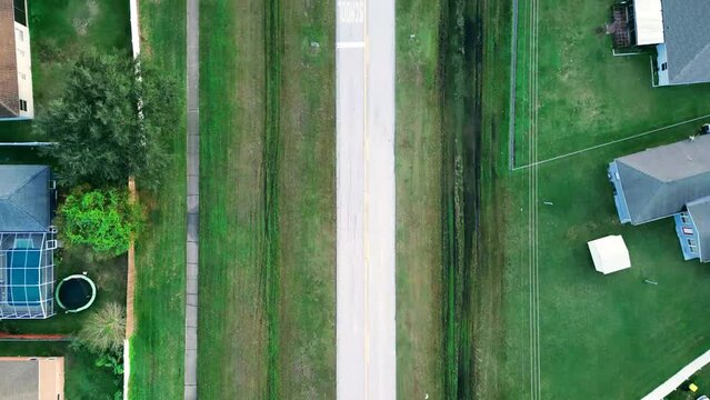 Aerial view of cars driving on a country road in grassland with houses on both sides in Kissimmee