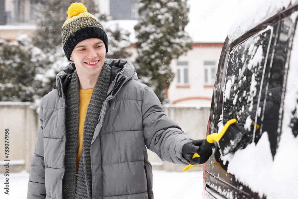 Wall mural Man cleaning snow from car window outdoors