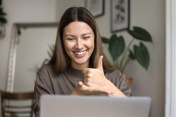 Cheerful hearing disability therapist talking on video conference call at laptop, speaking to...