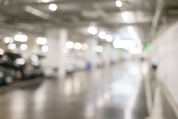 Blurred image of many cars parked in the parking lot under the building to go shopping in the mall which has a good care of safety bright parking There is a CCTV box recording.