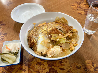 Katsudon, Japanese food, a bowl of rice topped with a deep-fried breaded pork cutlet, egg, vegetables, and condiments.