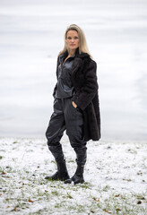 Portrait of a young beautiful woman in black coat on winter nature