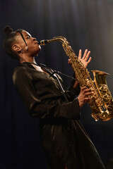 Side view portrait of passionate African American woman playing saxophone on stage in jazz music...