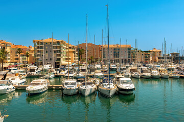 Fototapeta na wymiar Yachts and boats and residential buildings on background in Frejus, France.