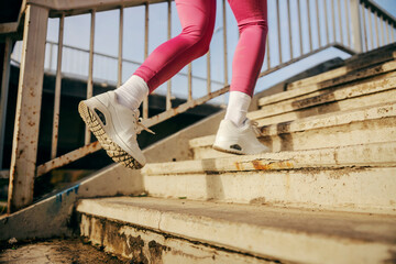 Sportswoman's feet running up the staircase outside in urban exterior.