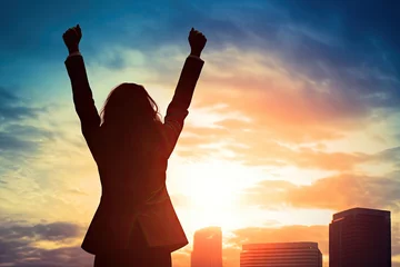 Fotobehang young business woman celebrating success in victory with raised hands, silhouette style © Yuthachai