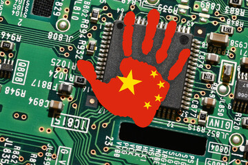 Microchip on electronic board with handprint with the colors of Chinese Flag. Concept for global battle and monopoly on microchip manufacturing between China, Taiwan and USA