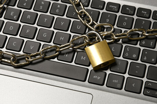 Computer security concept with an iron chain and padlock on the laptop keyboard