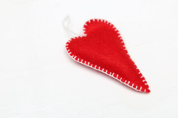 Handmade red felt heart on white background with copyspace.