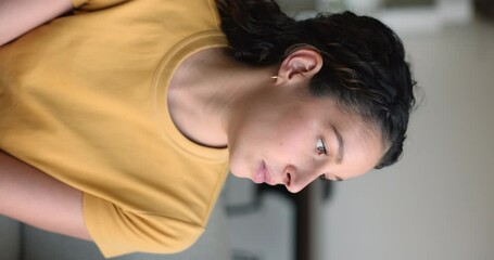 Young pensive Latina woman sit on sofa looking away deep in ponders, daydream, feels confused due to personal issues, search solution, decision, thinks alone at home, vertical shot. Thoughts, concerns