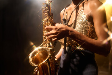 Close up of unrecognizable female musician playing jazz music focus on golden saxophone, copy space