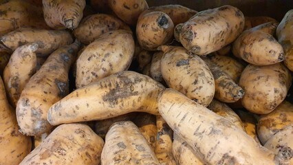 Close up pile of fresh sweet potatoes sold at the market as a background.