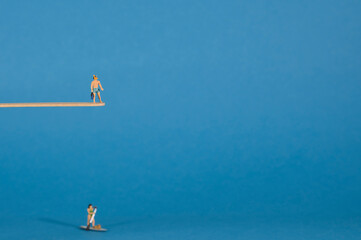 A diver stands on a diving board, blue background