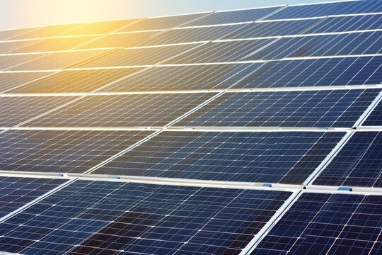 Close-up view of solar panels with blue sky background, highlighting sustainable energy infrastructure. Sustainable energy concept depicted through close-up of solar panels against a clear blue sky