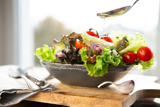 Colorful salad with fresh ingredients prepared with a spoon of olive oil in a ceramic bowl. Healthy nutrion concept for fitness and spring diet. 