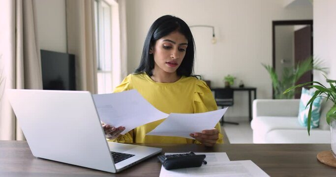 Desperate young Indian woman makes expenses and personal earnings analysis feels disappointed looks desperate, experiences lack of money to pay taxes and bills. Overspending, debt, financial troubles