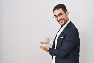 Handsome business hispanic man standing over white background inviting to enter smiling natural with open hand