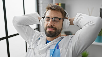 Chill mode, young hispanic guy in doctor's uniform, relaxed, listening to music with headphones in...