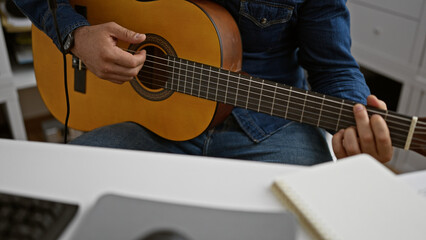 Obraz premium Captivating young hispanic man engrossed in playing a classic guitar melody at a music studio indoors, showcasing his musical talent