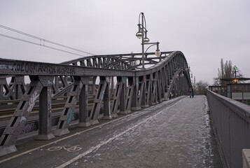 Berlin, Germany - Jan 06, 2024: Berlin wall at Place of 9 November 1989 in a cloudy winter day. Bosebrucke on Bornholmer Street. Former border crossing between GDR and FRG. Selective focus