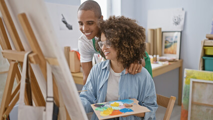 Confident man and woman artists, joyfully smiling and drawing together in a vibrant art studio